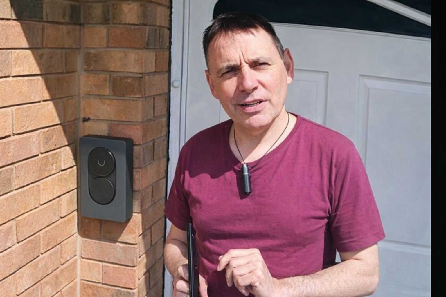 En man står bredvid en installerad Zaptec laddbox på en tegelvägg.